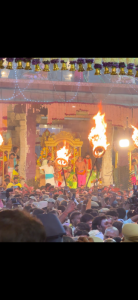 "Arunachala Hill lit by the Maha Deepam flame during Karthigai Deepam 2024 in Tiruvannamalai, with devotees holding oil lamps."